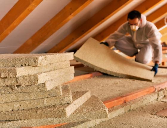 person laying insulation in attic